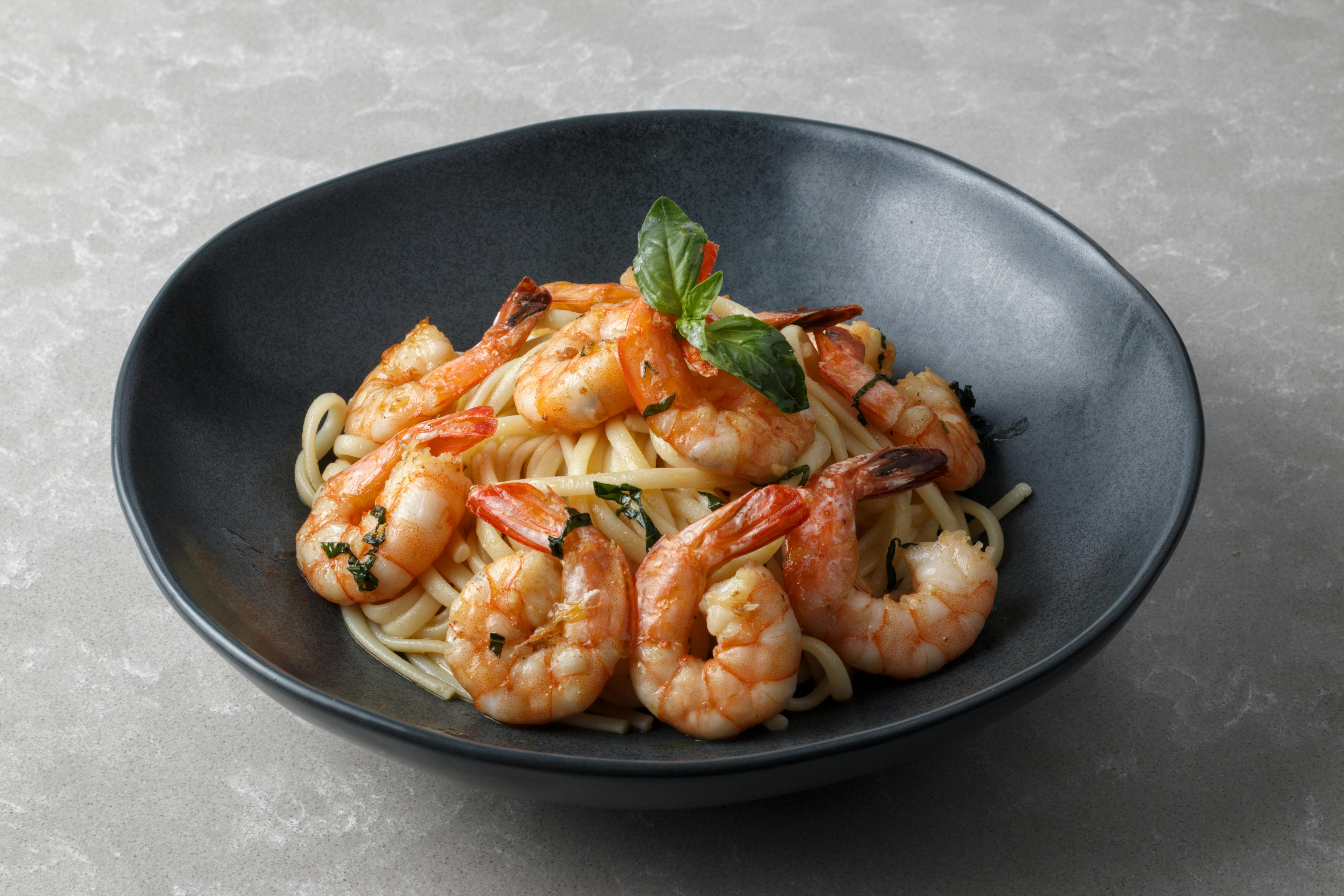 A serving of finished garlic shrimp pasta in a gray bowl