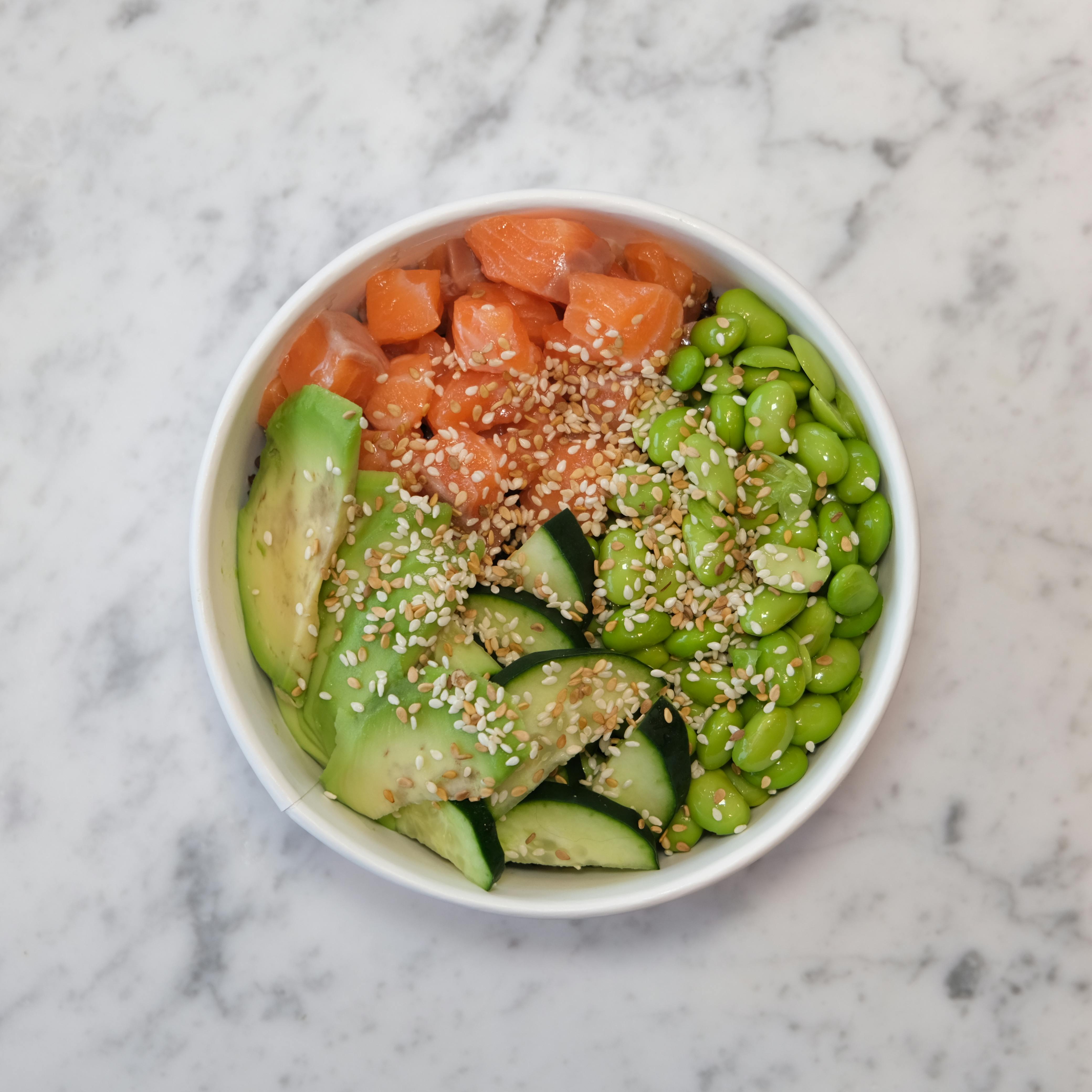 A serving of finished salmon poke bowl in a white bowl
